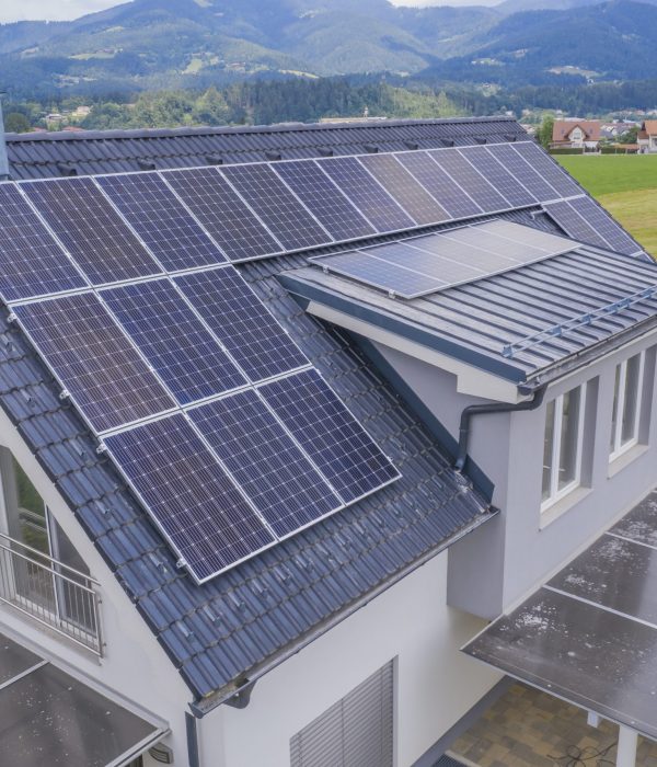 A high angle shot of a private house situated in a valley with solar panels on the roof
